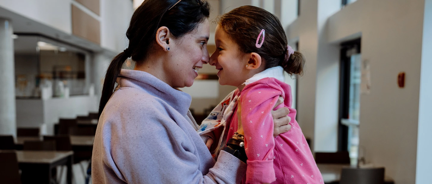 mother holding daughter up and both touching noses and smiling