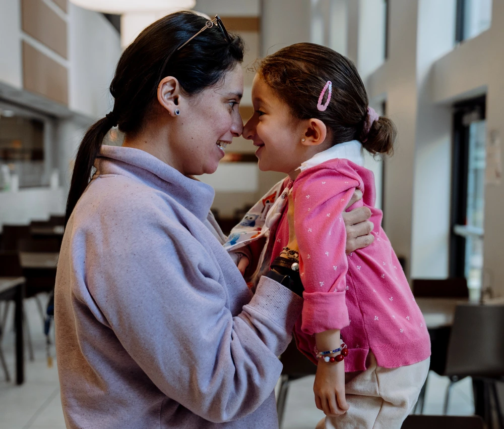 mother holding daughter up and both touching noses and smiling