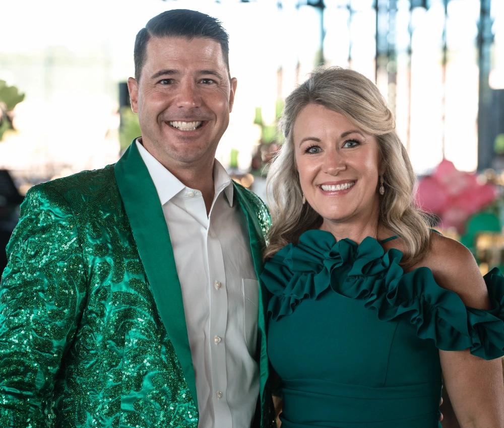 couple in matching green formal wear for Red Shoe Rendezvous Gala
