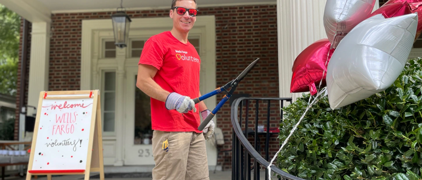 volunteer trimming hedges outside smiling brightly