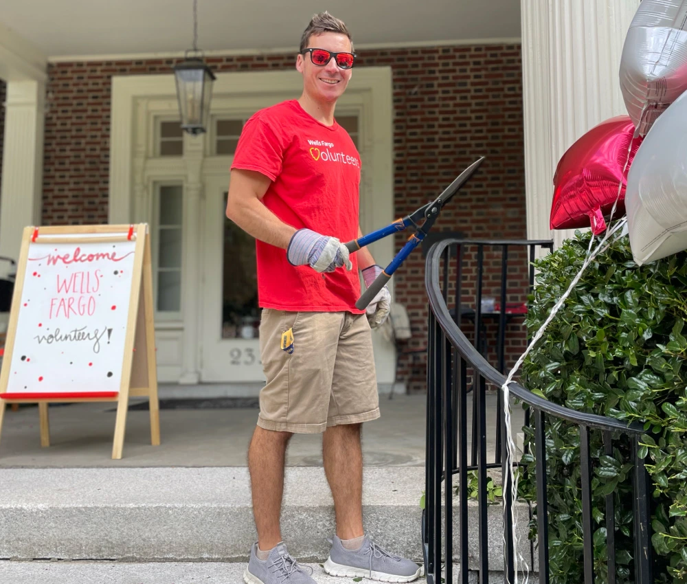 volunteer trimming hedges outside smiling brightly