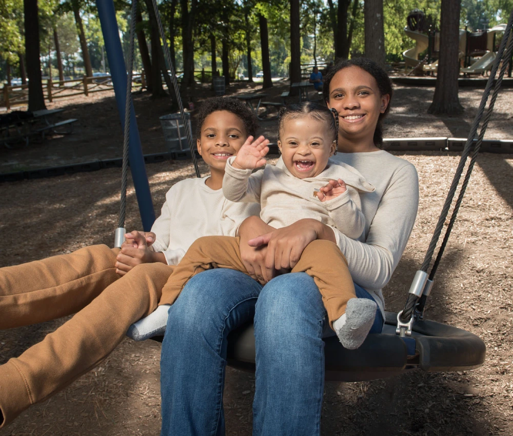 Mother with two young children sitting together on a family swing