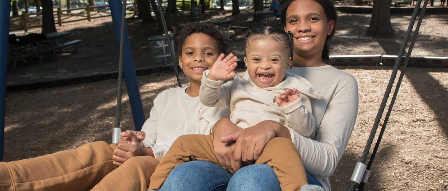 Mother with two young children sitting together on a family swing