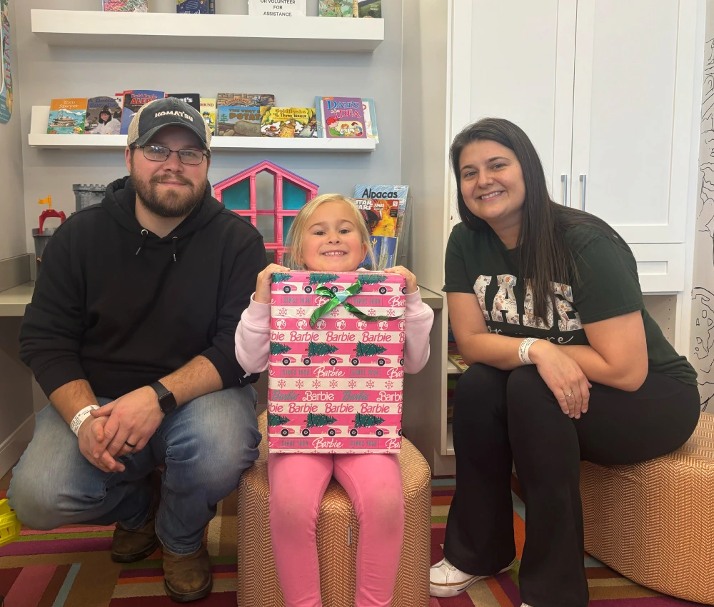 mother and father with their daughter holding a wrapped present
