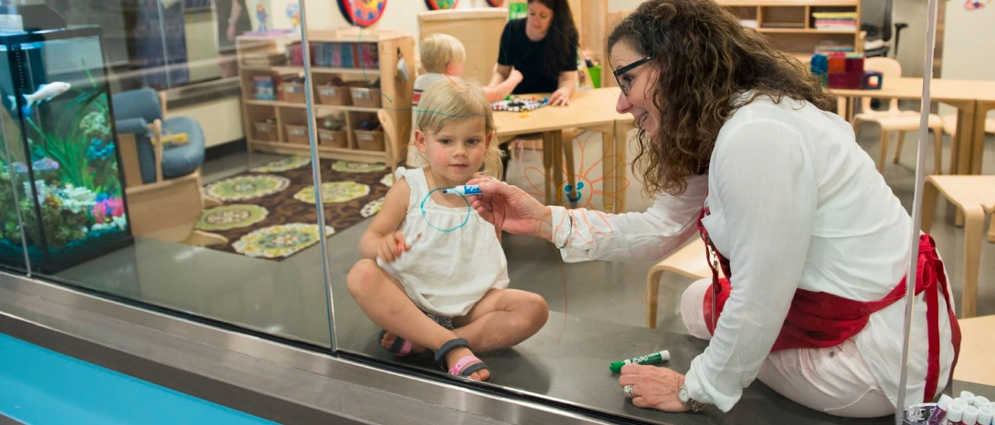 volunteer and small child playing together inside sibling center