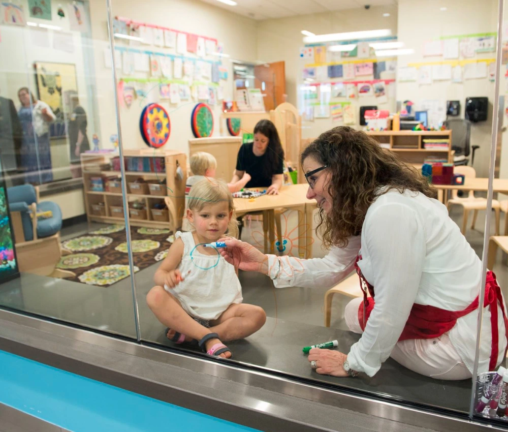 volunteer and small child playing together inside sibling center