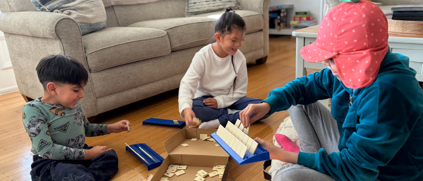 three siblings sitting together on the floor playing a board game